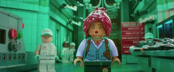 Movie still from “The Lego Batman Movie” (2017), directed by Chris McKay – A woman with red hair is standing next to a building; Close Up shot, Over the shoulder angle