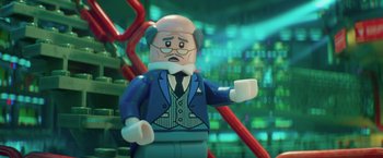 Movie still from “The Lego Batman Movie” (2017), directed by Chris McKay – A lego figure of an old man wearing a suit and tie; Close Up shot, Over the shoulder angle