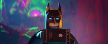 Movie still from “The Lego Batman Movie” (2017), directed by Chris McKay – A lego batman holding an iphone in front of a neon background; Close Up shot, Low angle