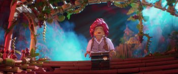 Movie still from “The Lego Batman Movie” (2017), directed by Chris McKay – A lego character is standing in front of a stage; Medium shot, Over the shoulder angle