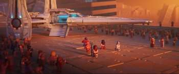 Movie still from “The Lego Movie 2: The Second Part” (2019), directed by Mike Mitchell – A group of people sitting in a parking lot next to an airplane; Extreme Wide shot, High angle