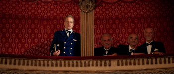 Movie still from “The Life Aquatic with Steve Zissou” (2004), directed by Wes Anderson – Two men in suits are sitting in a theater; Medium shot, Low angle