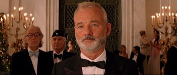 Movie still from “The Life Aquatic with Steve Zissou” (2004), directed by Wes Anderson – A man in a suit and a bow tie standing next to another man in a suit; Close Up shot, Low angle