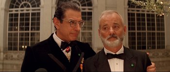 Movie still from “The Life Aquatic with Steve Zissou” (2004), directed by Wes Anderson – A man in a suit and tie standing next to another man in a suit and tie; Close Up shot, Low angle