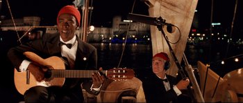 Movie still from “The Life Aquatic with Steve Zissou” (2004), directed by Wes Anderson – A man playing a guitar while another man watches; Medium shot, Over the shoulder angle