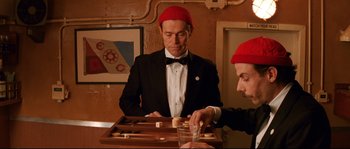Movie still from “The Life Aquatic with Steve Zissou” (2004), directed by Wes Anderson – A man in a red hat playing a game of backgammon; Medium shot, High angle