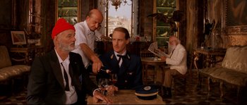Movie still from “The Life Aquatic with Steve Zissou” (2004), directed by Wes Anderson – A group of people sitting around a table; Medium shot, Over the shoulder angle