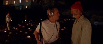 Movie still from “The Life Aquatic with Steve Zissou” (2004), directed by Wes Anderson – A man wearing headphones and talking to another man; Medium shot, Over the shoulder angle