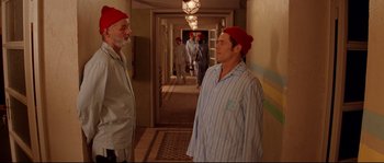 Movie still from “The Life Aquatic with Steve Zissou” (2004), directed by Wes Anderson – Two men in pajamas and red hats in a hallway; Medium shot, Over the shoulder angle
