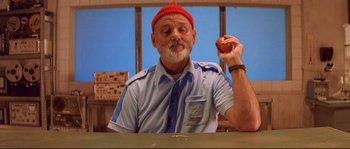 Movie still from “The Life Aquatic with Steve Zissou” (2004), directed by Wes Anderson – An older man holding an apple in his right hand; Medium shot, Low angle