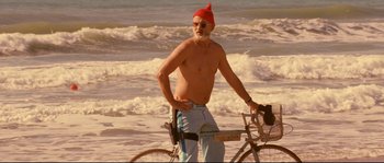 Movie still from “The Life Aquatic with Steve Zissou” (2004), directed by Wes Anderson – An old man with a red hat is standing next to a bike; Medium shot, Low angle