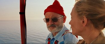 Movie still from “The Life Aquatic with Steve Zissou” (2004), directed by Wes Anderson – A man and a woman wearing sunglasses and a red hat; Close Up shot, Over the shoulder angle