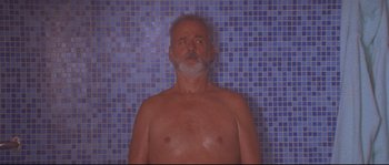 Movie still from “The Life Aquatic with Steve Zissou” (2004), directed by Wes Anderson – An older man is taking a shower in a bathroom; Medium shot, Low angle