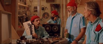 Movie still from “The Life Aquatic with Steve Zissou” (2004), directed by Wes Anderson – A group of men sitting around a table; Medium shot, Low angle
