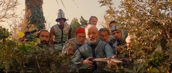 Movie still from “The Life Aquatic with Steve Zissou” (2004), directed by Wes Anderson – A group of people in a field with bushes; Medium shot, Low angle