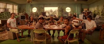 Movie still from “The Life Aquatic with Steve Zissou” (2004), directed by Wes Anderson – A group of people sitting around a table eating; Wide shot, High angle
