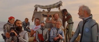Movie still from “The Life Aquatic with Steve Zissou” (2004), directed by Wes Anderson – A group of men in full body suits sitting on a boat; Wide shot, High angle