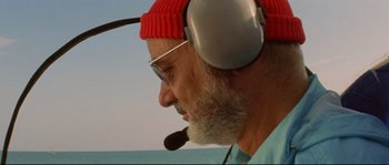 Movie still from “The Life Aquatic with Steve Zissou” (2004), directed by Wes Anderson – An older man wearing a red hat and headphones; Close Up shot, Low angle