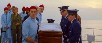 Movie still from “The Life Aquatic with Steve Zissou” (2004), directed by Wes Anderson – A group of men standing next to each other near an open casket; Medium shot, Low angle