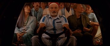 Movie still from “The Life Aquatic with Steve Zissou” (2004), directed by Wes Anderson – An old man sitting in front of a group of people; Medium shot, Low angle