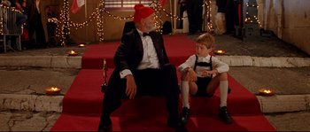 Movie still from “The Life Aquatic with Steve Zissou” (2004), directed by Wes Anderson – An older man and a young boy sitting on a red carpet; Medium shot, Over the shoulder angle
