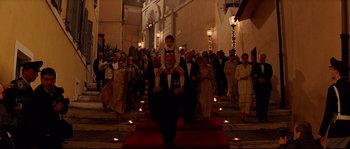 Movie still from “The Life Aquatic with Steve Zissou” (2004), directed by Wes Anderson – A man carrying a young boy on his shoulders in front of a crowd of onlookers; Wide shot, Low angle