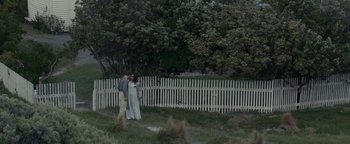 Movie still from “The Light Between Oceans” (2016), directed by Derek Cianfrance – A man and a woman standing next to a white picket fence; Wide shot, High angle