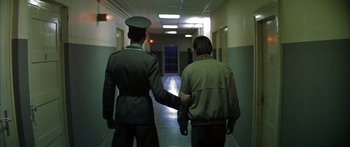 Movie still from “The Lives of Others” (2006), directed by Florian Henckel von Donnersmarck – Two men in uniform are holding hands in a hallway; Medium shot, Low angle