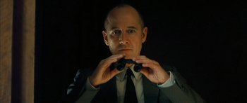 Movie still from “The Lives of Others” (2006), directed by Florian Henckel von Donnersmarck – A man in a suit and tie holding a pair of binoculars up to his face; Close Up shot, Low angle