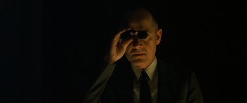 Movie still from “The Lives of Others” (2006), directed by Florian Henckel von Donnersmarck – A man in a suit and tie holding a pair of sunglasses; Close Up shot, Low angle
