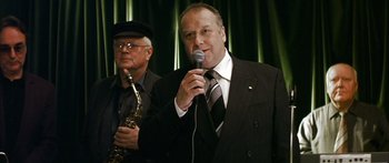 Movie still from “The Lives of Others” (2006), directed by Florian Henckel von Donnersmarck – A man in a suit and tie holding a microphone; Close Up shot, Low angle