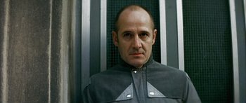 Movie still from “The Lives of Others” (2006), directed by Florian Henckel von Donnersmarck – A man with a bald head wearing a gray jacket; Close Up shot, Low angle