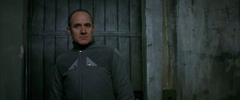 Movie still from “The Lives of Others” (2006), directed by Florian Henckel von Donnersmarck – A man standing in front of a wooden wall; Medium shot, Low angle