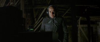 Movie still from “The Lives of Others” (2006), directed by Florian Henckel von Donnersmarck – An older man wearing headphones while looking at a computer screen; Medium shot, Over the shoulder angle