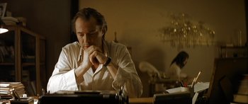 Movie still from “The Lives of Others” (2006), directed by Florian Henckel von Donnersmarck – A man sitting at a table with his hands clasped together; Medium shot, Low angle