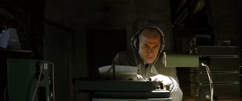 Movie still from “The Lives of Others” (2006), directed by Florian Henckel von Donnersmarck – A man wearing headphones and sitting in front of an old typewriter; Medium shot, Low angle