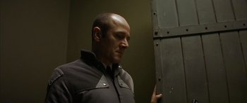 Movie still from “The Lives of Others” (2006), directed by Florian Henckel von Donnersmarck – A man in a black shirt is looking at a metal door; Close Up shot, Low angle