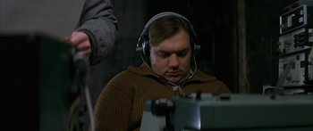 Movie still from “The Lives of Others” (2006), directed by Florian Henckel von Donnersmarck – A man with headphones on looking at a computer screen; Close Up shot, High angle