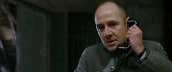 Movie still from “The Lives of Others” (2006), directed by Florian Henckel von Donnersmarck – A man is talking on a phone while sitting down; Close Up shot, Low angle