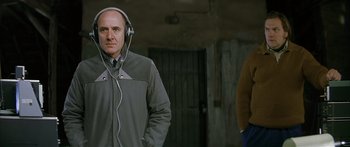 Movie still from “The Lives of Others” (2006), directed by Florian Henckel von Donnersmarck – A man wearing headphones and standing next to another man; Medium shot, Low angle