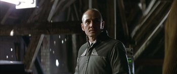 Movie still from “The Lives of Others” (2006), directed by Florian Henckel von Donnersmarck – A bald man in a jacket is looking at the camera; Close Up shot, Low angle