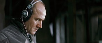 Movie still from “The Lives of Others” (2006), directed by Florian Henckel von Donnersmarck – A bald man wearing headphones looking to his left; Close Up shot, Low angle