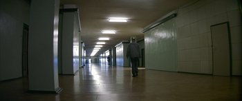 Movie still from “The Lives of Others” (2006), directed by Florian Henckel von Donnersmarck – A man walking down a long hallway in a building; Wide shot, High angle
