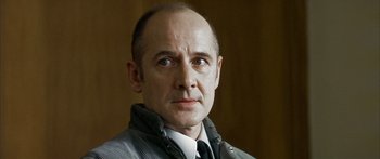 Movie still from “The Lives of Others” (2006), directed by Florian Henckel von Donnersmarck – A man with a bald head wearing a jacket and a tie; Close Up shot, Low angle
