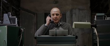 Movie still from “The Lives of Others” (2006), directed by Florian Henckel von Donnersmarck – A man talking on a phone while sitting at a desk; Medium shot, Low angle
