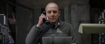 Movie still from “The Lives of Others” (2006), directed by Florian Henckel von Donnersmarck – A man holding a phone up to his ear while sitting in front of a computer; Close Up shot, Low angle