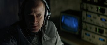 Movie still from “The Lives of Others” (2006), directed by Florian Henckel von Donnersmarck – An older man wearing headphones while sitting in front of a television; Close Up shot, Over the shoulder angle