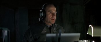 Movie still from “The Lives of Others” (2006), directed by Florian Henckel von Donnersmarck – A man wearing headphones looking at a computer screen; Close Up shot, Low angle