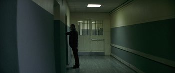 Movie still from “The Lives of Others” (2006), directed by Florian Henckel von Donnersmarck – A man standing in a room next to a wall; Wide shot, Over the shoulder angle