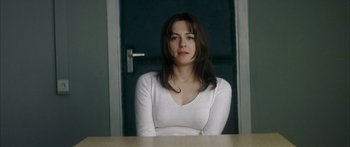 Movie still from “The Lives of Others” (2006), directed by Florian Henckel von Donnersmarck – A woman sitting at a table in front of an open door; Close Up shot, Over the shoulder angle